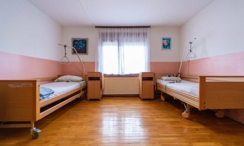 dvokrevetna soba s noćnim ormarićima i velikim prozorom u domu za starije osobe Zagreb